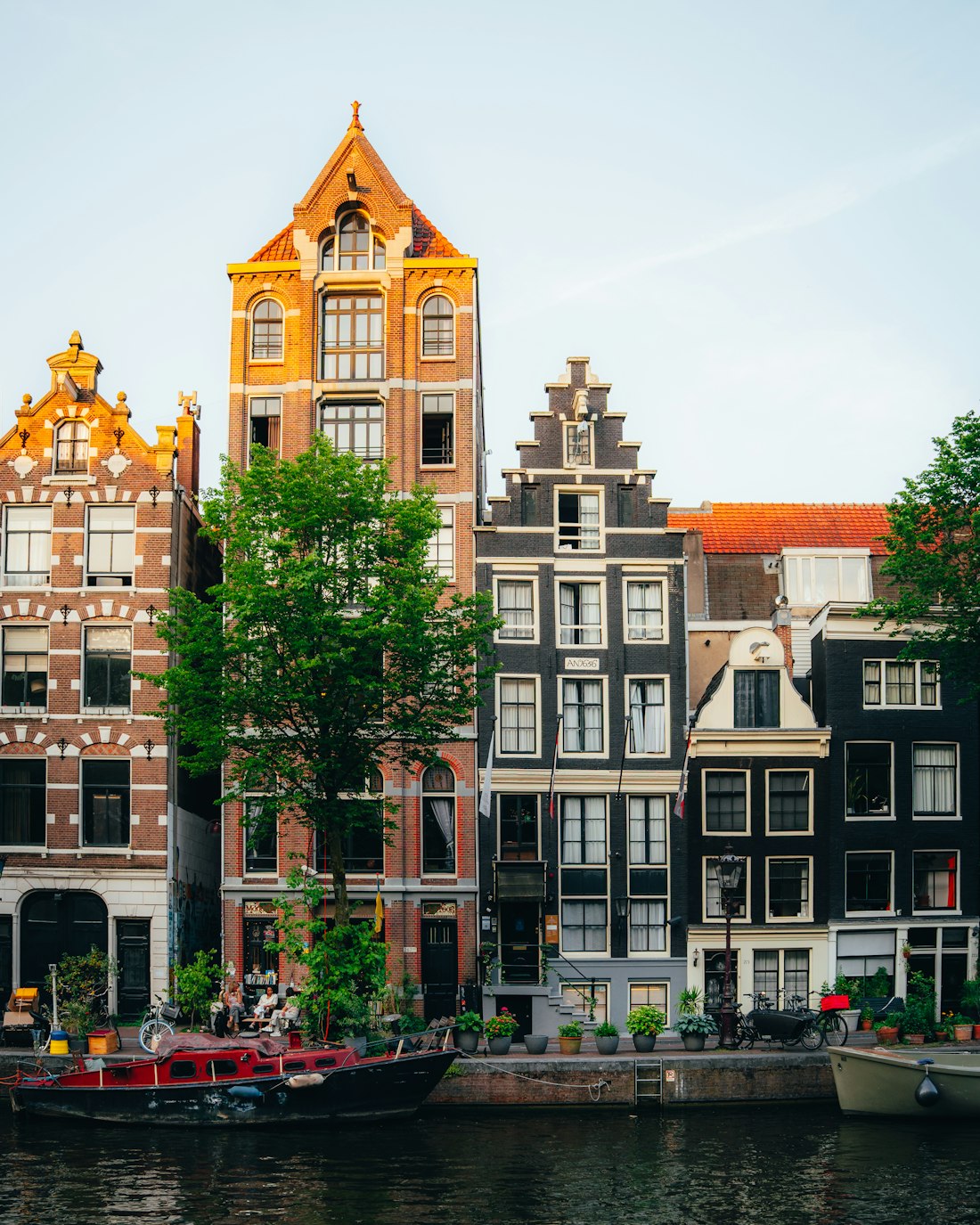 Rij Amsterdamse grachtenpanden met eigen voordeuren in warm avondlicht